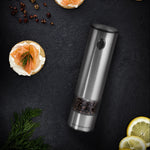 Pepper grinder with sliced lemon and pepper on a dark surface