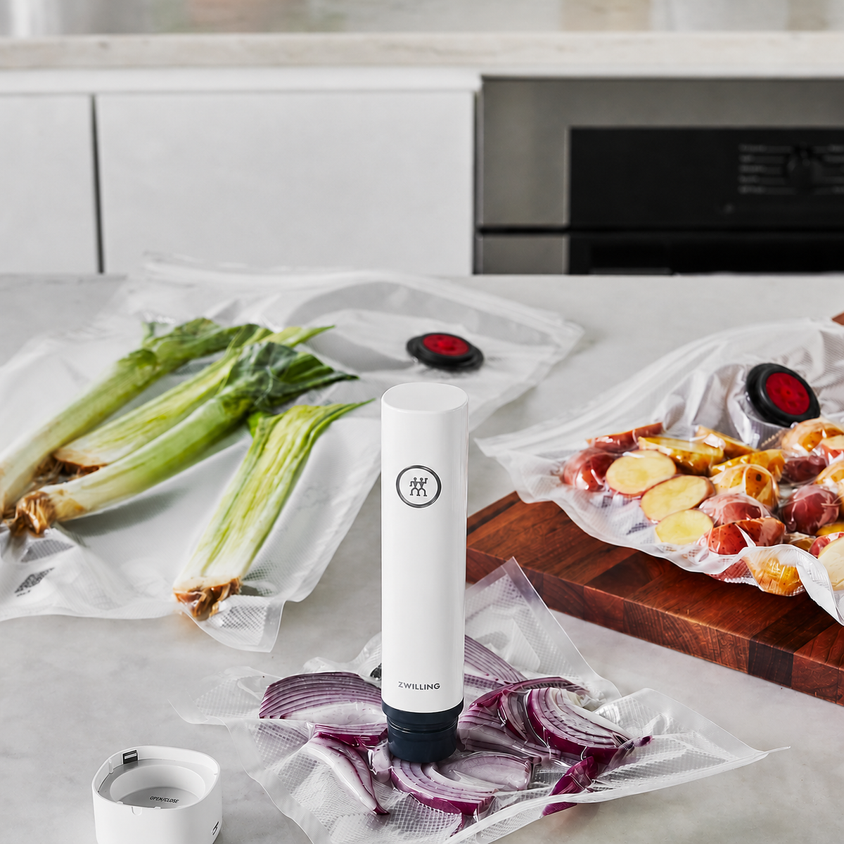 ZWILLING vacuum pump sealing bags of onions, leeks, and potatoes on a kitchen counter