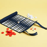 A roll-up backgammon set with pieces spread out on a yellow background, including a blue foldable case with zipper compartment.