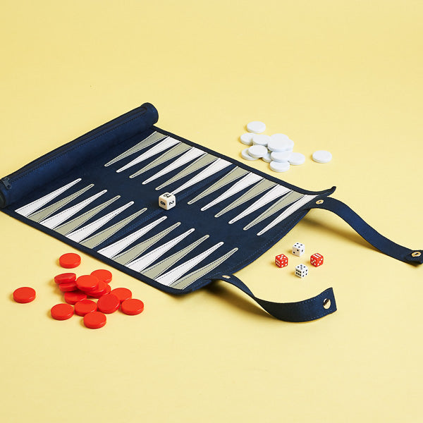 A roll-up backgammon set with pieces spread out on a yellow background, including a blue foldable case with zipper compartment.